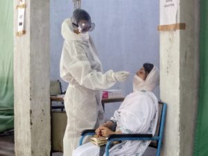 A health worker wearing PPE suit collects swab sample of a woman for Covid-19 test