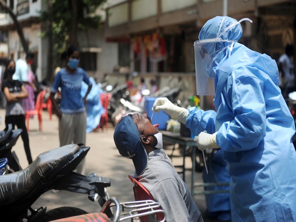 A doctor wearing PPE suit takes a swab sample of a resident at a COVID-19 testing drive