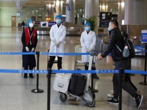 Medical officials monitor a thermal scanner as passengers arrive at the airport in Changsha