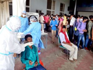 A healthcare worker collects swab sample from migrant workers