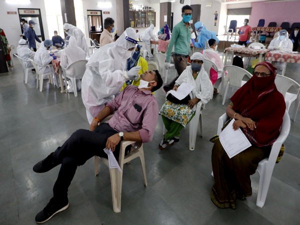 Healthcare workers wearing PPE kits collect swab samples from municipal school teachers for COVID-19 testing