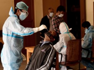 A health worker in PPE kit collects a nasal sample from a man for a COVID test