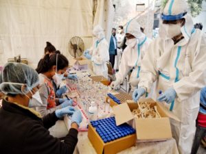 Health workers wearing a PPE kit collect swab samples