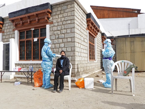 Health worker in PPE kit collects nasal sample from a woman for Covid-19 test