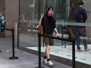 A person wearing a protective respirator enters a queue in Sydney