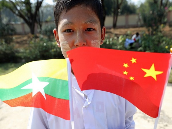 Myanmar students hold Myanmar and Chinese flags as they prepare to welcome Chinese President Xi Jinping outside of the airport in Naypyitaw