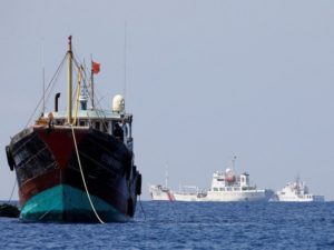 China Coast Guard vessels patrol past a Chinese fishing vessel at the disputed Scarborough Shoal