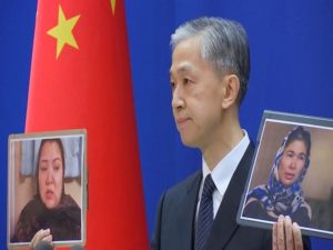 Chinese Foreign Ministry spokesman Wang Wenbin holds pictures while speaking during a news conference in Beijing