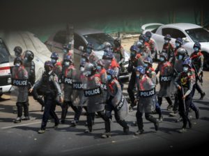 Riot police officers advance on pro-democracy protesters during a rally against the military coup in Yangon