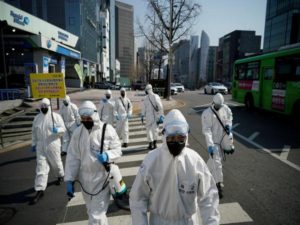 South Korean soldiers in protective gear sanitize a street at a shopping district in Seoul