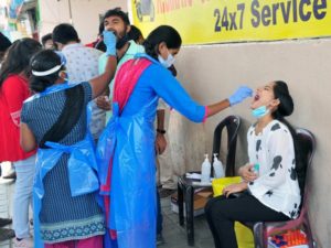 A medic collects a swab sample of a woman for the COVID-19 test