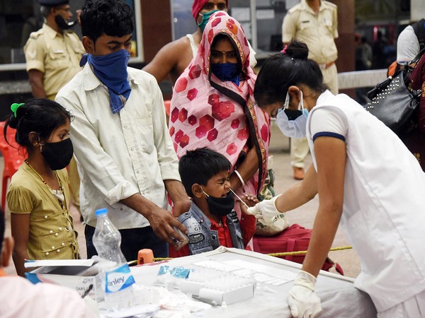 Health worker takes swab samples of a migrant family arriving from Maharashtra