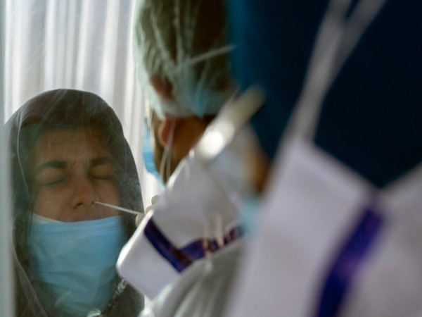 A healthcare worker takes the swab sample of a woman