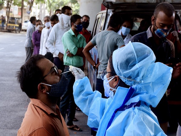 A medics in PPE kit collects a nasal sample from a man for a covid19 rapid test,