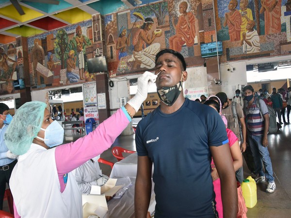 A healthcare worker collects a nasal sample of a passenger for the COVID-19 testing