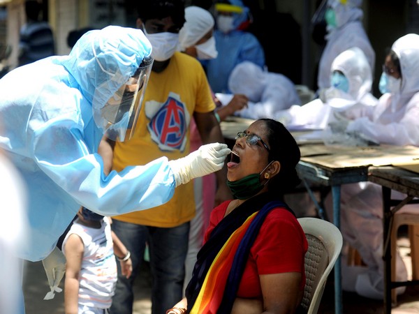 Medical worker takes the sample of a woman for COVID-19 testing at Matunga