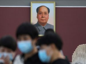 Tourists are seen near a portrait of China's late Chairman Mao Zedong at Tiananmen Square, in Beijing