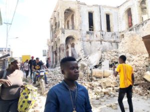 People walk along the street next to destroyed buildings following an earthquake in Jeremie