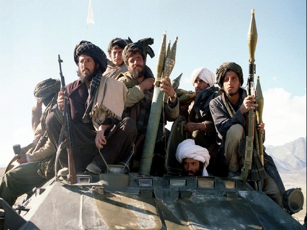 Armed members of Taliban Islamic students' movement sit atop an armoured personnel carrier as they p..