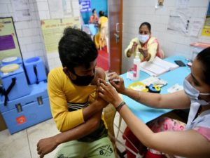 A beneficiary reacts while receiving a dose of the Covid-19 vaccine at a health centre