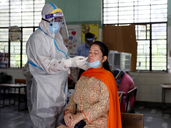 A health official collects a swab sample from a woman to test for the COVID-19