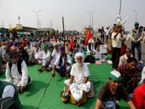 Farmers sitting with placards and flags at the demonstration site during the ongoing farmer protest