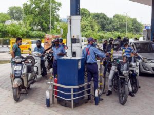 A fuel station attendant pumps petrol into vehicles