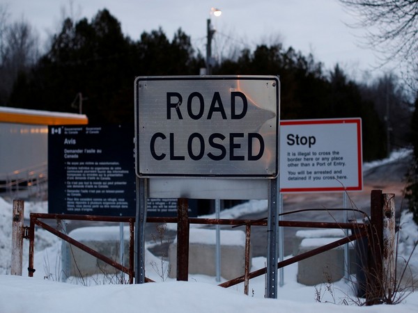 Signs are pictured at the US-Canada border as seen from Roxham Road in Champlain