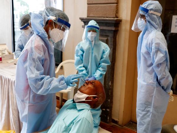 a health worker wearing personal protective equipment (PPE) collects a nasal sample from a man for COVID-19 test