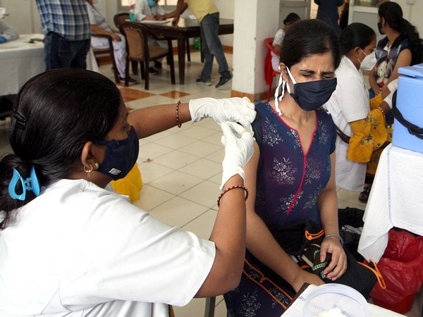 A healthcare worker administers a dose of a COVID-19 vaccine to a woman 