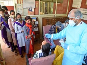 A healthcare worker collects swab sample of a student