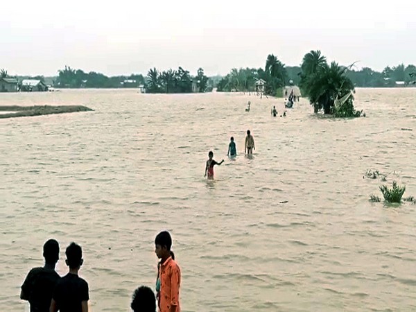 People wade through a waterlogged street triggered by incessant rainfall,