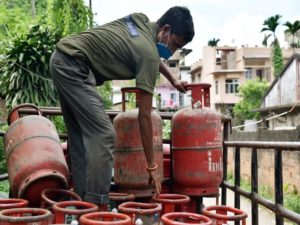 A worker carries an LPG gas cylinder for delivery