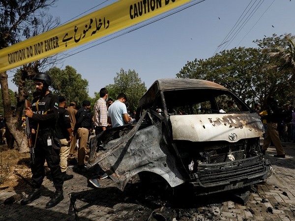 Police officers and crime scene unit gather near a passenger van, after a blast at the entrance of the Confucius Institute University of Karachi