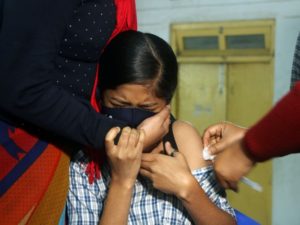 A girl reacts as she receives a dose of the COVID-19 vaccine