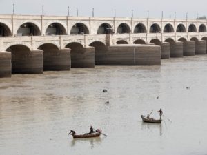 Fishermen row their boats as they catch fish on the river Indus at Sukkur Barrage in Sukkur