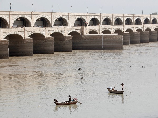 Fishermen row their boats as they catch fish on the river Indus at Sukkur Barrage in Sukkur