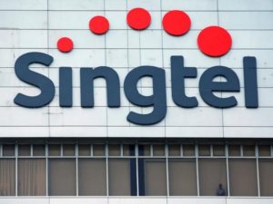 FILE PHOTO A man looks out of the window under a Singtel signage at their head office in Singapore