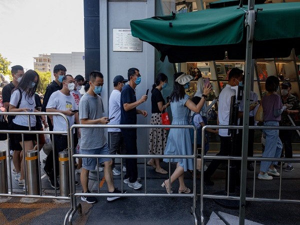 People show their health code app as they enter a business area before office hours, in Beijing