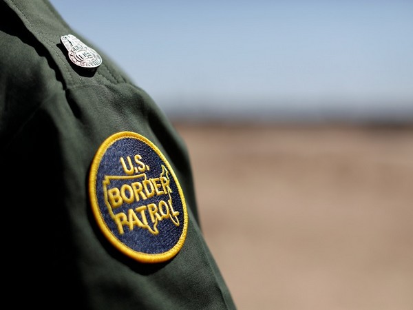 U.S. Customs and border patrol agent walks near the border wall in San Luis, Arizona