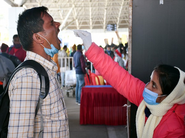 A healthcare worker collects a nasal swab sample of a passenger