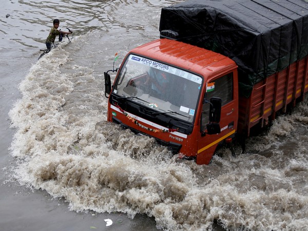 A cyclist reacts seeing the flow of water after the truck passed through a waterlogged road