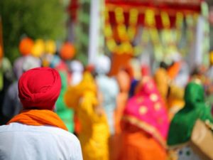 sikh man with red turban during an outdoor parade and more people