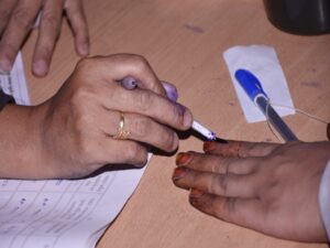 A polling official applies inedible ink on a voter's finger after casting vote for the Gujarat Assembly elections