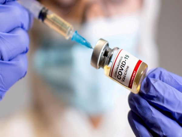 gFILE PHOTO: A woman holds a medical syringe and a small bottle labeled "Coronavirus COVID-19 Vaccine