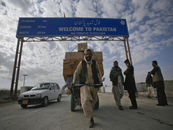 A Pashtun man passes a road sign while pulling supplies towards the Pakistan-Afghanistan border crossing in Chaman